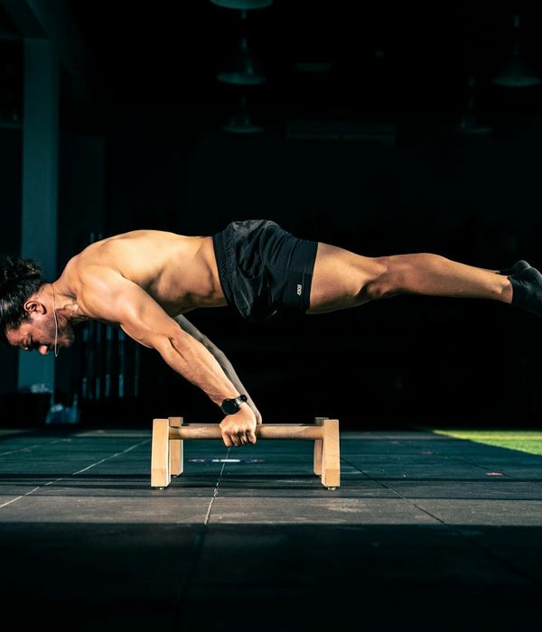 Man performing a controlled bodyweight exercise in a dark studio.