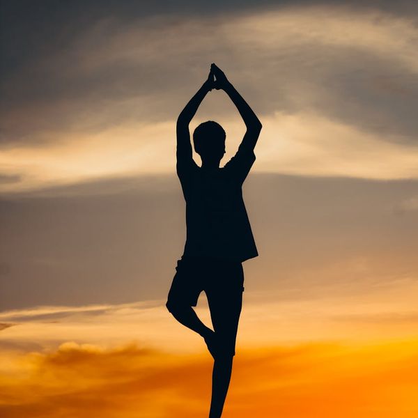 Silhouette of a person balancing on one leg during sunset.